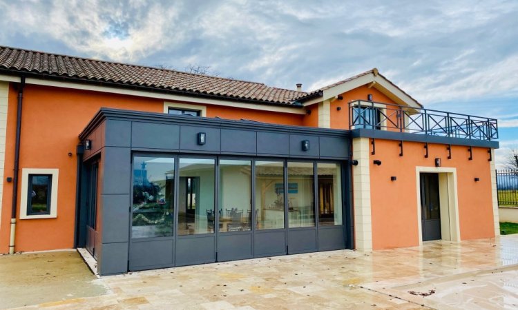 Rénovation et extension d’une habitation d’exception près de Villefranche-sur-Saône (69), intégrant des baies accordéon, une toiture vitrée et des stores sur-mesure.