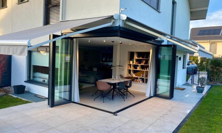 Splendide extension de pièce de vie réalisée grâce à une baie accordéon d’angle, offrant une ouverture maximale sur l’extérieur.