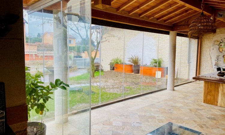 Conception et installation d’un système de fermeture de terrasse sur-mesure, harmonieusement intégré à cette habitation située dans l’Ain (01).